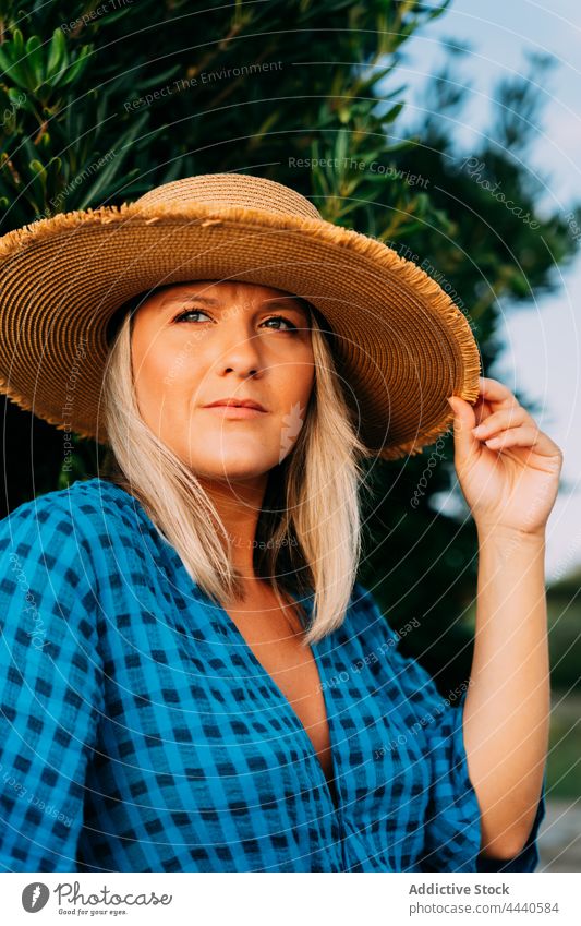 Dreamy traveler in straw hat against shrub wistful natural vacation reflective dreamy solitude woman portrait contemplative tourism garment trip