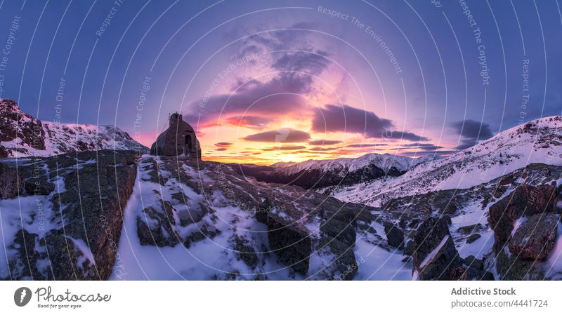 Aged stone house placed on top of under colorful sky at sunrise mountain nature sunset landscape environment highland slope rock travel countryside bright snow