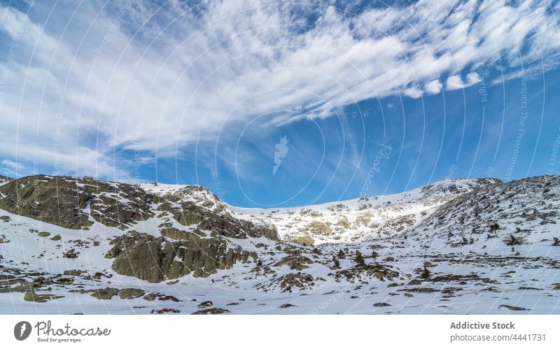 Snowy mountains under cloudy blue sky in daylight nature snow rocky highland ridge rough formation environment peak terrain picturesque slope range countryside