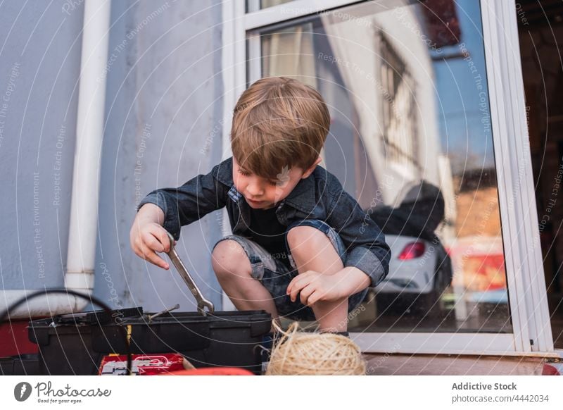 Boy taking wrench out of box in daylight boy take out curious childhood tool spare time instrument twine reflection glass door container attentive interested