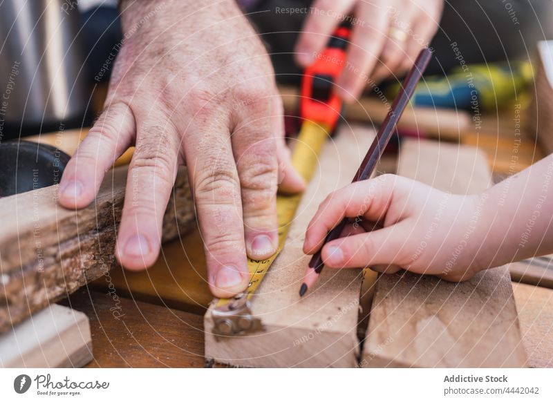 Crop father with son measuring wooden plank measure woodwork diy tape pencil handicraft help man precise boy interact tool childhood fatherhood spend time dad