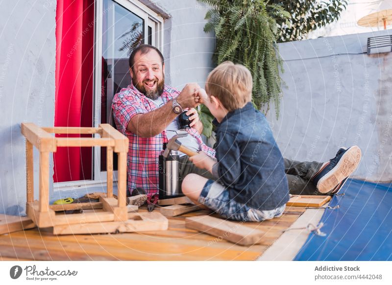 Smiling father with son bumping fists during woodwork dad fist bump agree smile diy craft spend time childhood man interact accept handwork handmade boy artisan