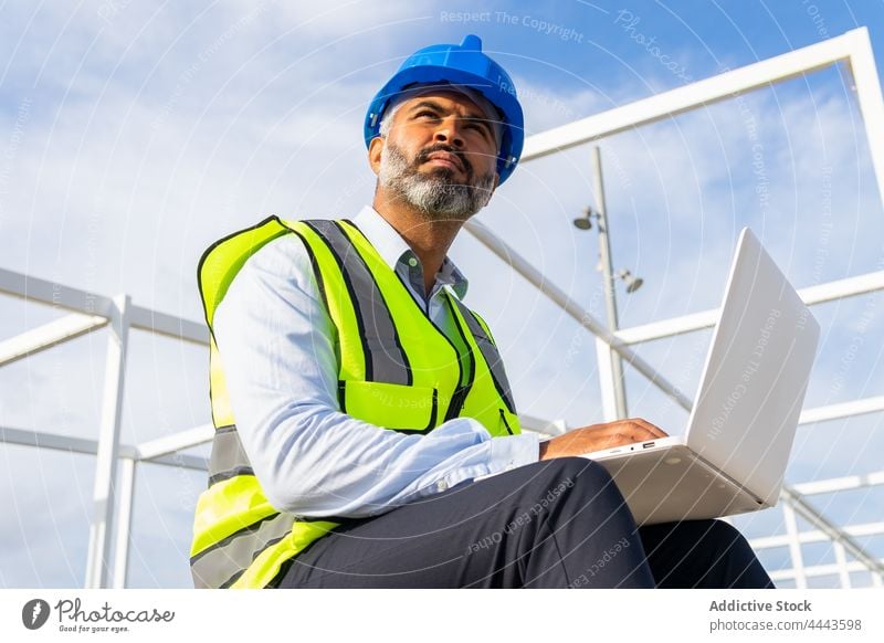 Inspector working on laptop under modern solar power station inspector internet uniform man using gadget device netbook engineer hardhat vest foreman male