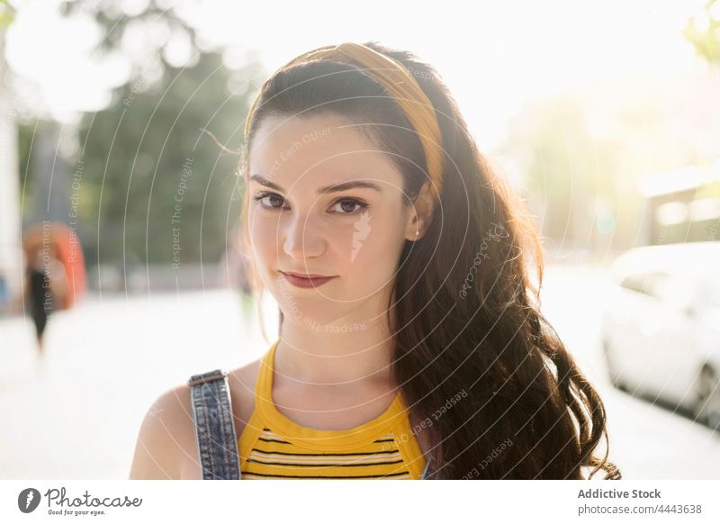 Charming woman standing on street charming personality style cool millennial posture appearance female feminine individuality brunette carefree denim gaze