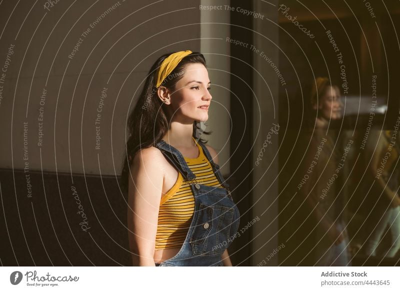 Confident woman in casual outfit and headband standing near building serious confident style cool gaze young individuality charming millennial female