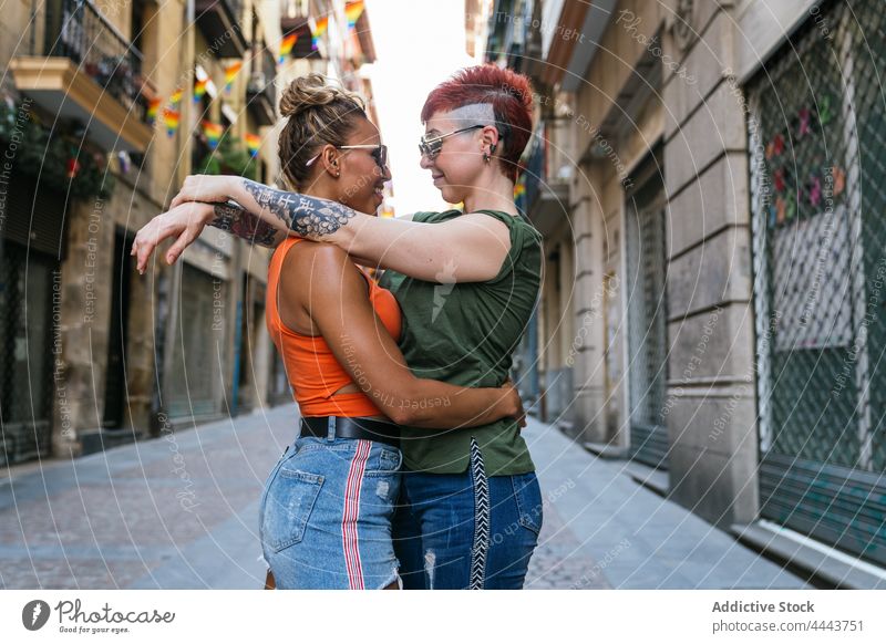 Cool happy homosexual girlfriends in moment of kiss on street couple embrace relationship love tattoo lgbt women pavement mindfulness amorous trendy mohawk