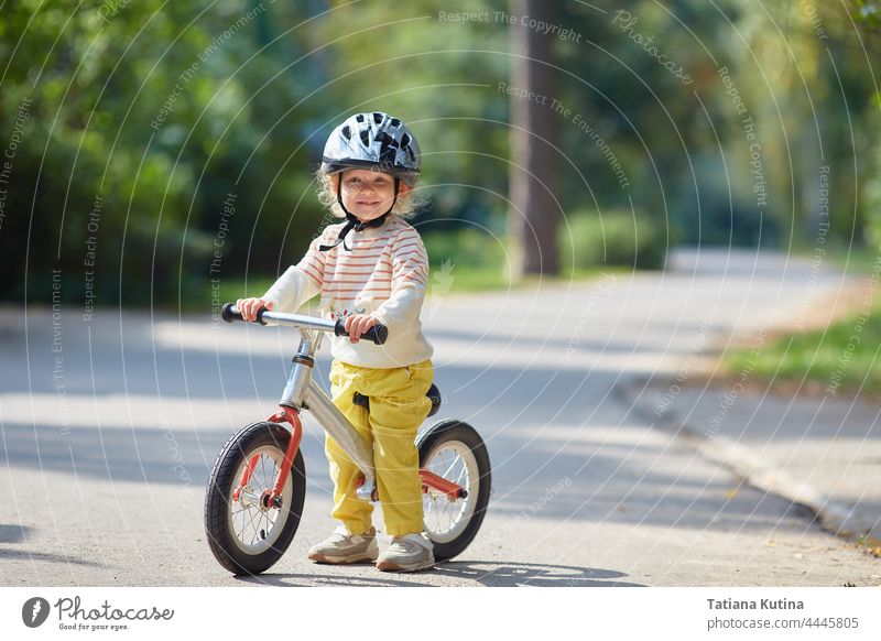 satisfied child on a balance bike in a helmet. On a sunny summer day. sport toddler bicycle baby kid park little happy fun boy girl ride play preschool young