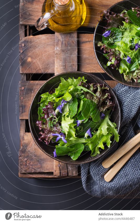 Delicious lettuce and wildflower salad in bowls on dark background healthy food vegetarian vegetable natural fresh oil delicious vitamin nutrient leaf portion