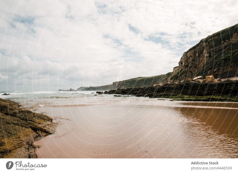 Mountain on beach against sea under cloudy sky mountain ocean seascape nature highland landscape horizon environment ecology moss slope shore summer foamy sandy