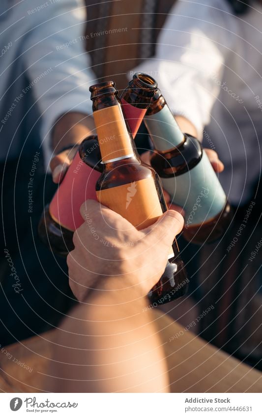 Group of friends clinking bottles of beer men woman cheers hangout gather bar male female together pub friendship drink alcohol weekend meeting toast party