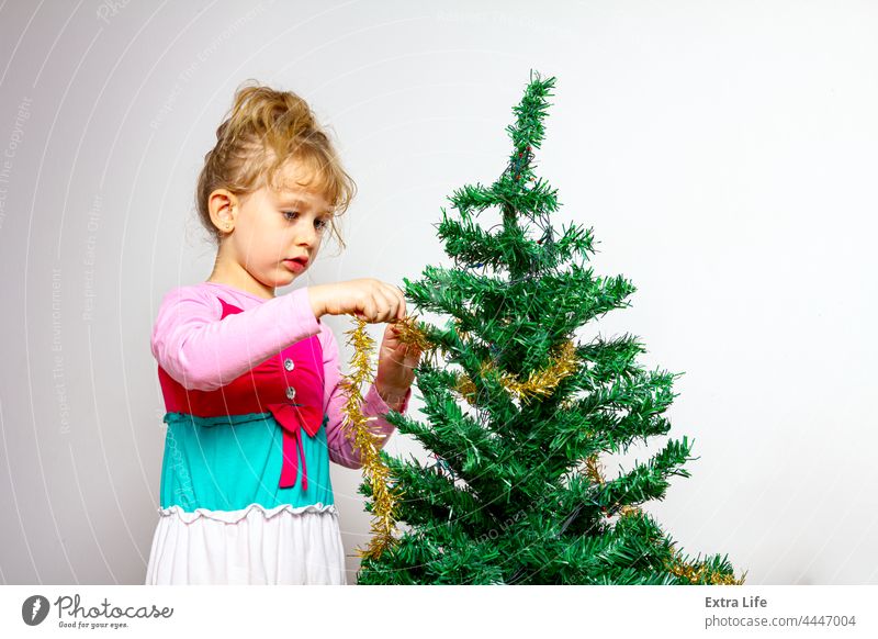 Child girl is arranging ornament decoration on artificial Christmas tree Adorable Arrange Artificial Assembly Blonde Caucasian Childhood Conifer Curve Cute