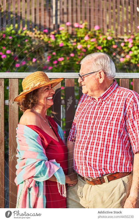 Senior cheerful couple standing near wooden fence laugh senior happy romantic relationship enjoy nature countryside fun woman together love bonding romance