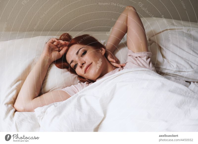 happy smiling young woman lying in bed after waking up wake bedroom morning stretch real people home adult person authentic lifestyle lady girl indoor caucasian