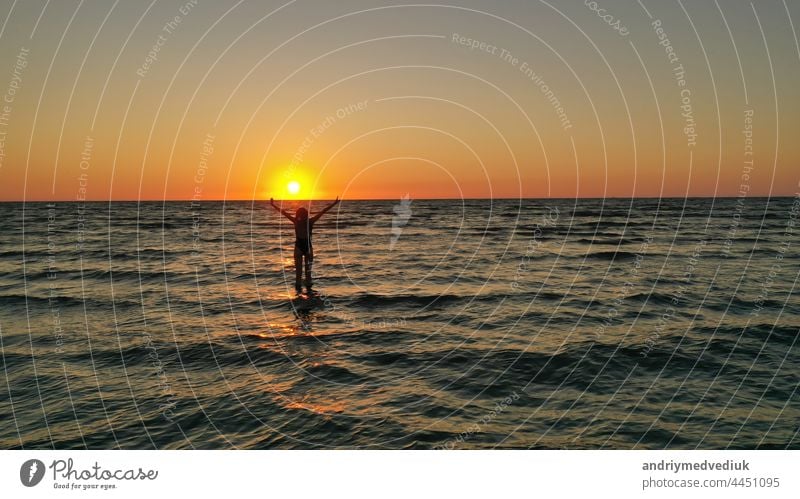 silhouette of a relaxed young girl in a bathing suit in the sea at sunrise. Happy Vacation Holiday Concept. woman happy beach sunset vacation holiday standing