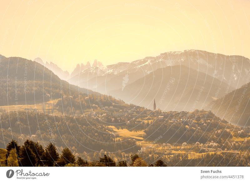 South Tyrolean mountain landscape with a view of the Three Peaks in the far distance Landscape mountains Three peaks Church sunbeam Spring Italy Dolomiti