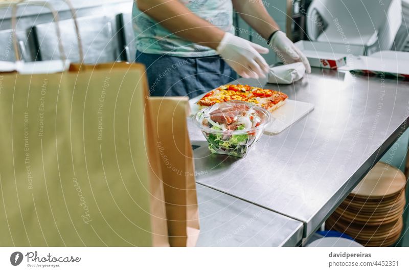 Unrecognizable cook packing takeaway orders restaurant kitchen preparing orders paper bag unrecognizable salad industrial kitchen package gloves hygiene