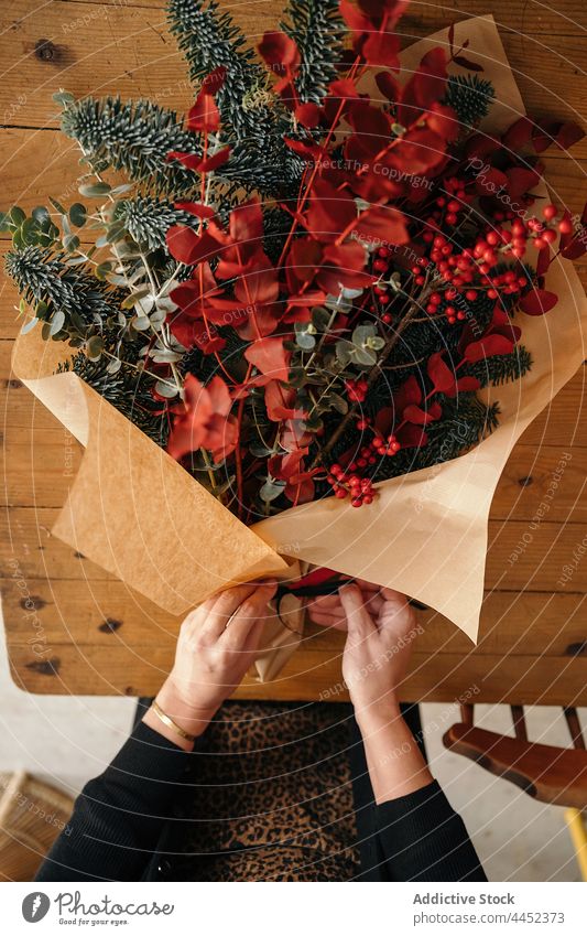 Florist arranging Christmas decoration in creative studio woman florist arrange bouquet christmas festive flower xmas new year female eucalyptus table event