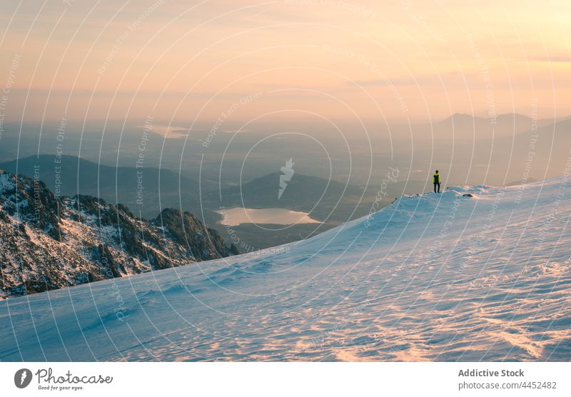 Hiker standing on snowy mountain under colorful sky at sunset person traveler highland range rock peak admire hiker spain sierra de guadarrama ridge landscape