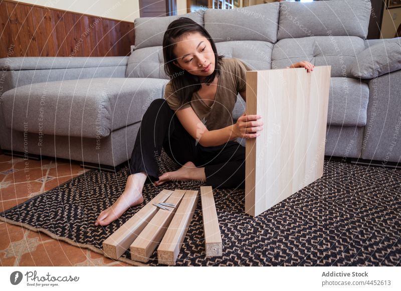 Asian woman assembling table in living room assemble attentive detail diy carpet ornament sofa home focus material barefoot concentrate couch sit rug floor