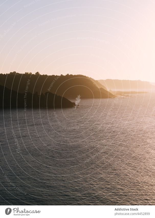 Mountains and rippled sea under light sky in evening mountain silhouette nature highland landscape untouched sunset ocean aqua scene wavy seawater rock idyllic