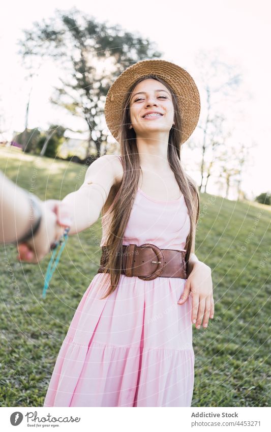 Cheerful teen holding crop friend by hand on meadow holding hands follow me cheerful spend time interact sincere portrait together partner smile candid content