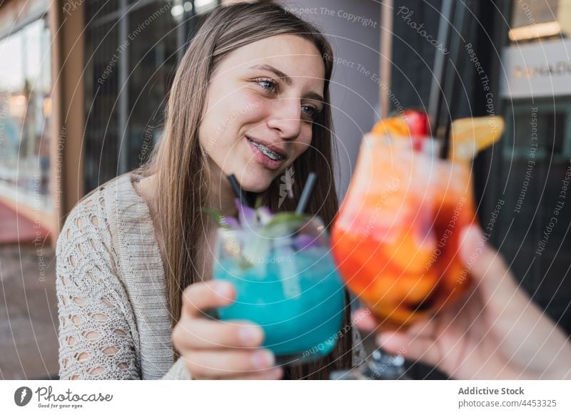 Smiling girlfriends clinking glasses of cocktails in street cafe refreshment drink beverage smile spend time cheerful interact pot content enjoy fruit delicious