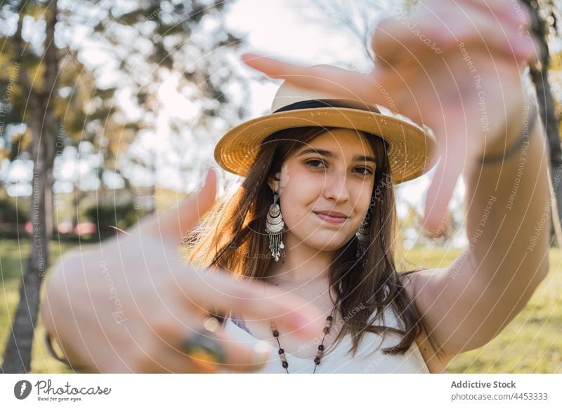 Teen showing frame gesture in summer park teen photo perspective picture smile brace sincere portrait friendly straw hat garment photography gaze symbol