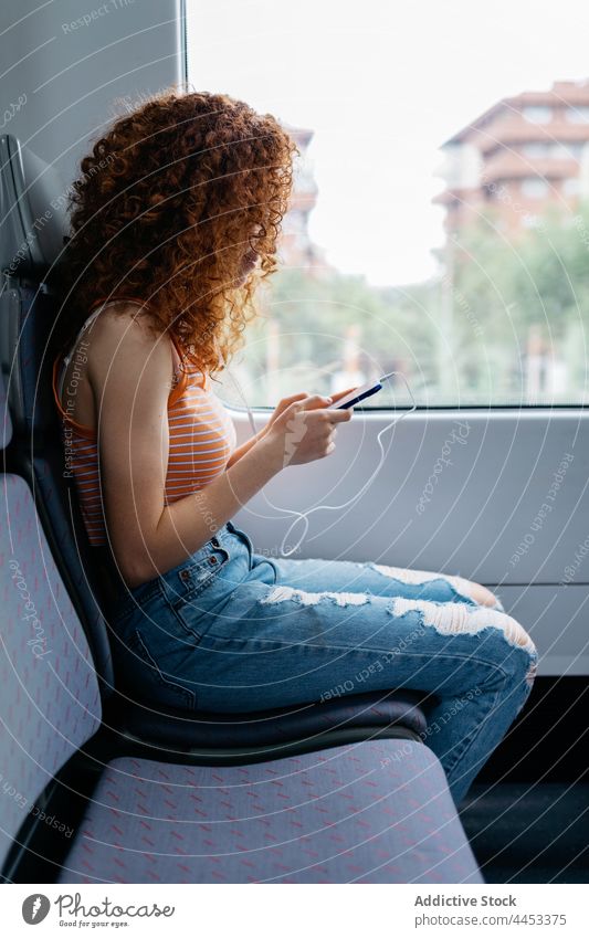 Passenger chatting on smartphone against window on train passenger internet online interested commute woman using gadget watching device text messaging surfing