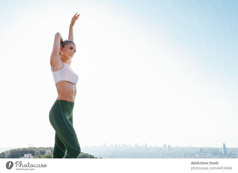 Sportswoman stretching arms during workout in city athlete sport arm raised hand behind head exercise training sky sportswoman active warm up healthy lifestyle