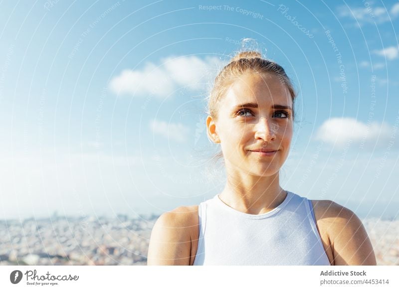 Sportswoman contemplating town in sunshine sportswoman confident dreamy sporty healthy lifestyle wellness vitality blue sky portrait sincere pleasant city enjoy