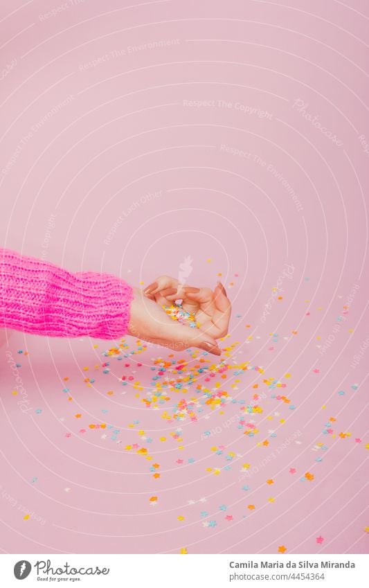 Womans hands covered with colorful star confetti on light pink background. Christmas and celebration concept. beauty birthday carnival christmas confectionery