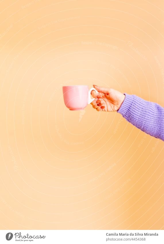 Closeup of female hands holding a light pink cup. Girl with beautiful nails. holding cup of tea or coffee. Studio photo. Photo for cropping. Empty. autumn