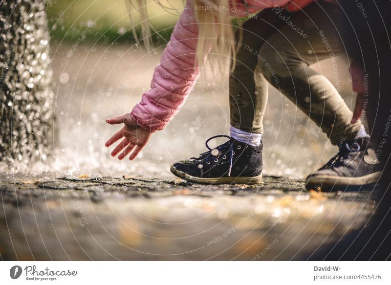 fascination water - child plays outside and feels with wet fingers for the water drops Child Fascinating Water Wet fun Joy Euphoric Playing Well Drops of water