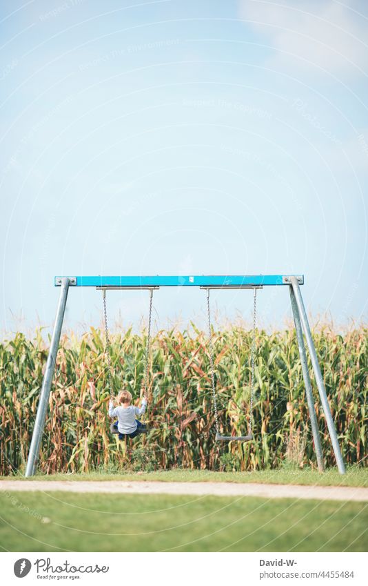 Child swinging on a swing in a playground Swing To swing fun Boy (child) Playground out Playing Joy Infancy Contentment