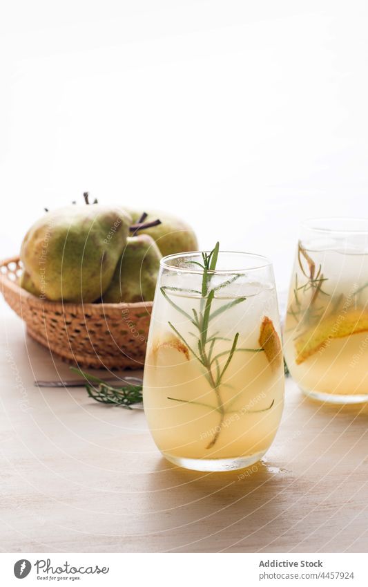 Glasses of fresh pear cocktail glass cold refreshment rosemary ice nonalcoholic beverage drink fruit sweet cool table liquid portion cube tasty delicious