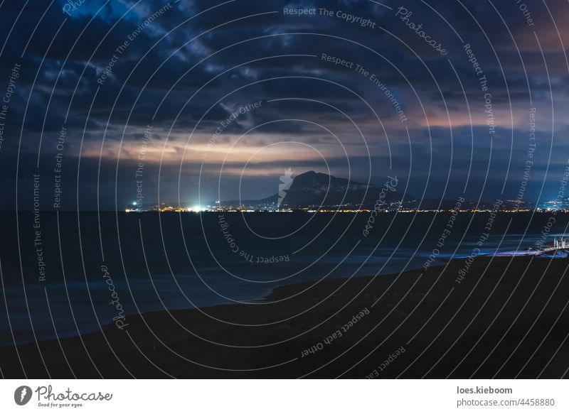 The coastline of Denia shined by moonlight seen from the beach of Daimus, Spain denia spain night clouds ocean water sea mediterranean cloudscape lights tourism