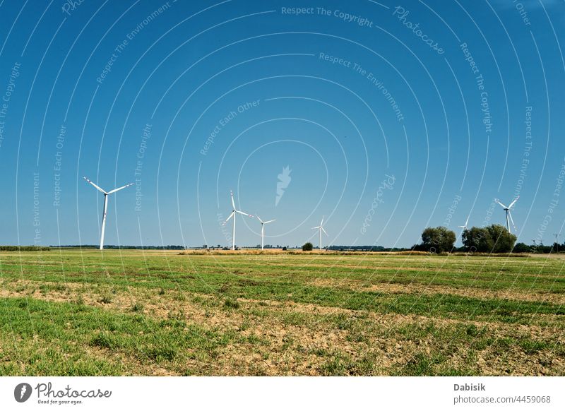 Windmill among agricultural fields. Wind turbine generator at summer day. Wind energy concept. Suistanable and renewable energy for climate protection. Green energy