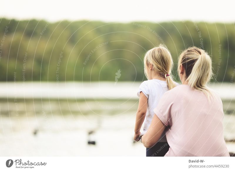 Mother and daughter out by the lake Daughter Lake at the same time in common Child Family Parents Observe Together