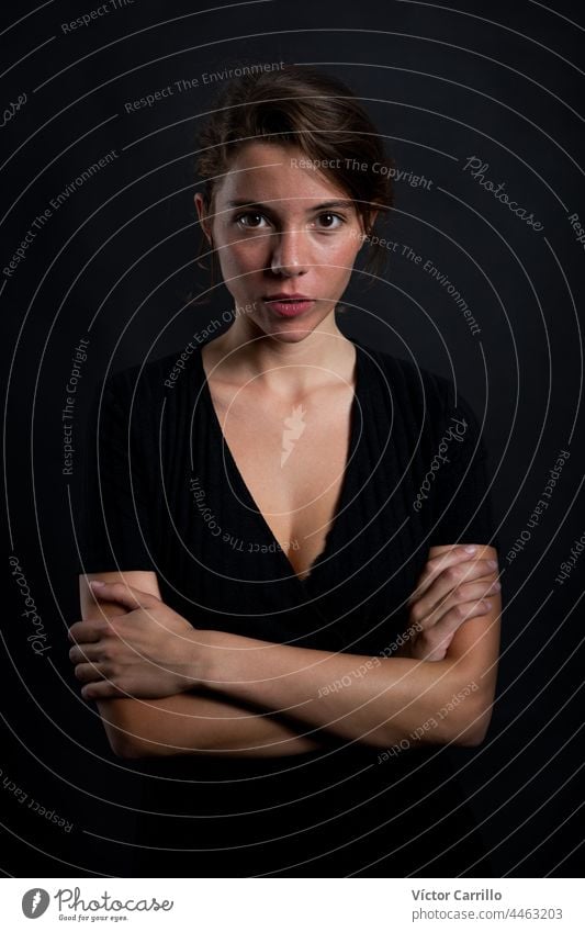 A young beautiful woman looking at the camera in a studio shot in black dress and background 20-25 adult attractive beauty brunette casual close-up concepts