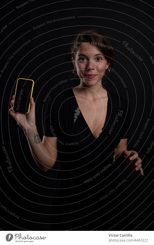 A young beautiful woman using a smartphone in a studio shot in black dress and background 20-25 adult attractive beauty brunette casual close-up concepts