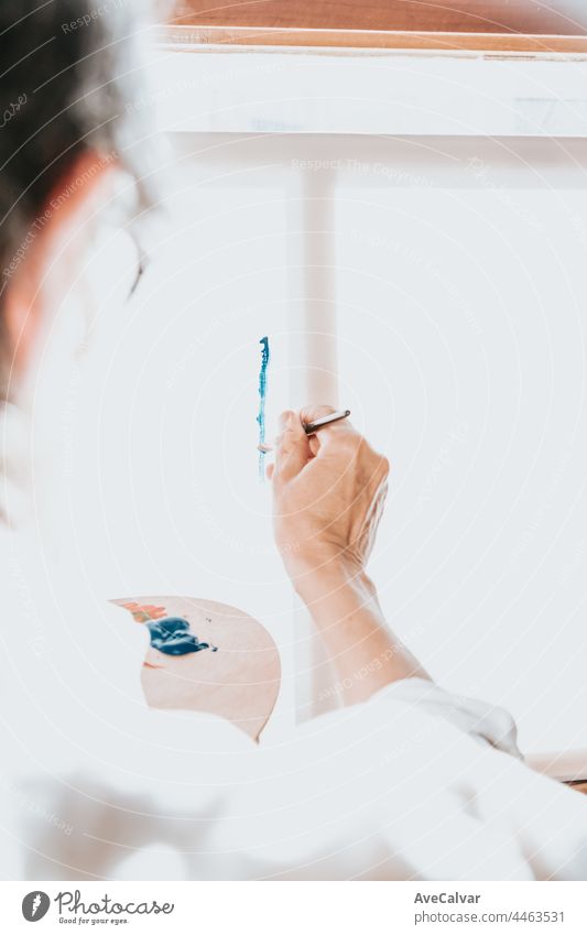 Close up of paintbrush painting in blue color in a canvas. Colorful image from an artist’s studio or a school showing creative education person woman hobby