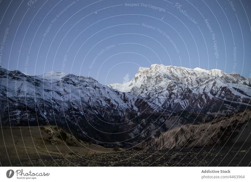 Snowy mountains under bright sky in evening range ridge slope snow valley rock stone formation landscape wildlife geology cliff high winter scenery peak