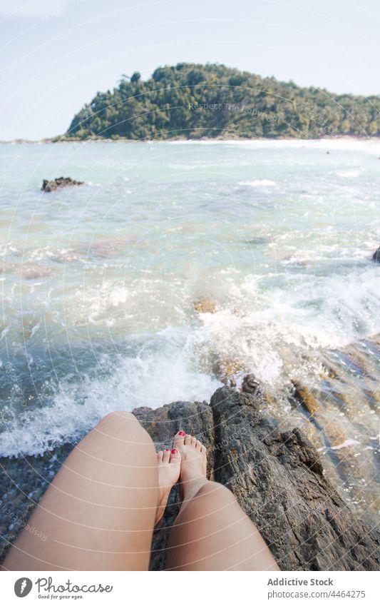 Crop traveler admiring stormy ocean from rock sea foamy nature highland landscape vacation woman rest admire contemplate pedicure flow water fluid motion energy