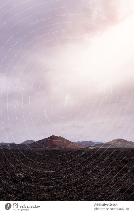 Dry pathway between black lava against volcanoes under light sky route direction nature highland landscape Bermeja volcano island mountain narrow scenic rough