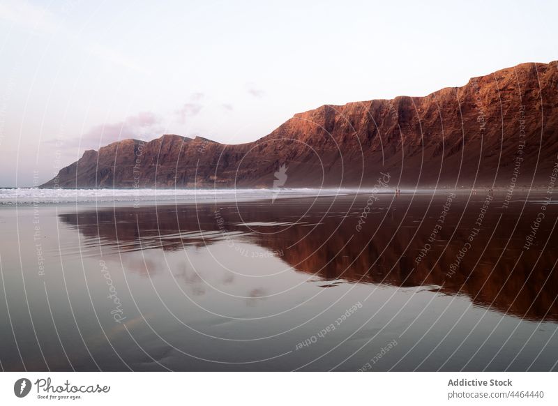 Sea shore with majestic mountain under cloudy sky beach ocean nature landscape highland massive island sea barren scenery picturesque scenic teguise ridge