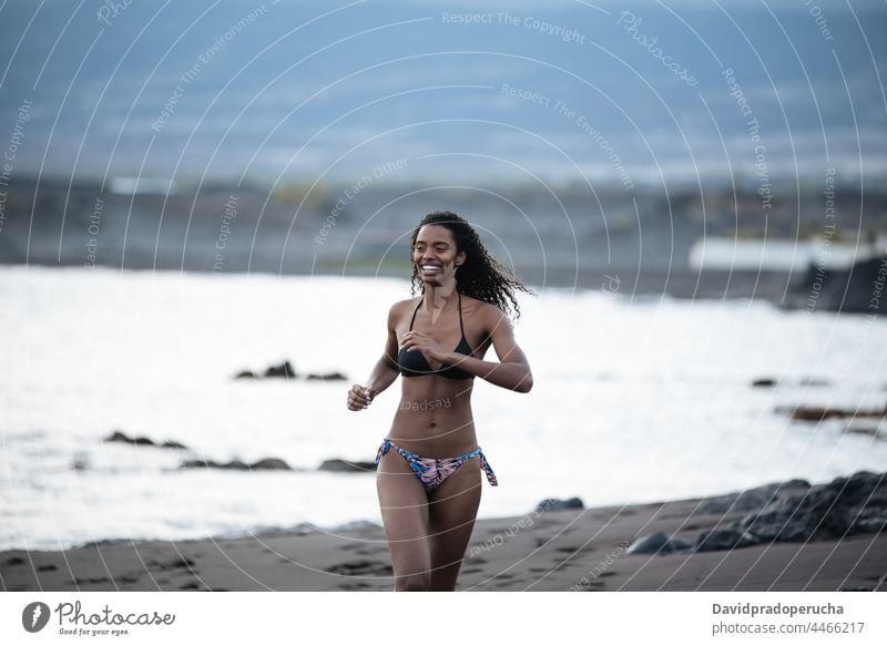 Woman in bikini in a volcanic beach woman ethnic island seaside beautiful fit santo antao smile african sexy cape verde holiday horizontal running fitness