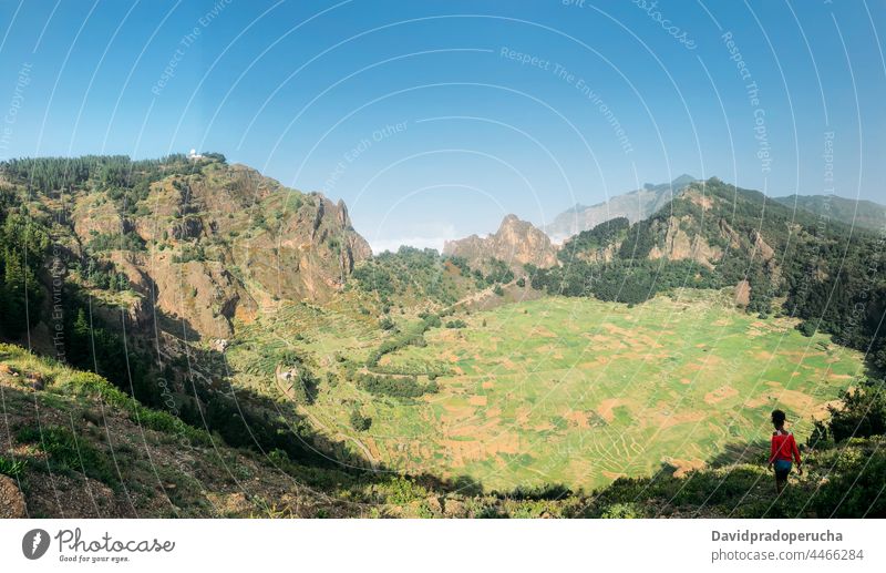 Scenic sunny mountain valley with person walking along scenic traveler panorama green peaceful summer picturesque stroll clear sky tree nature landscape