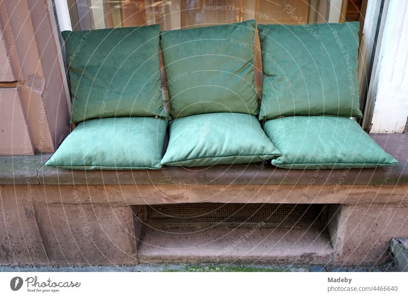 Elegant green seat cushions on red sandstone in the frame of a window in front of a hairdresser's in a beautiful old building in the North End of Frankfurt am Main in Hesse