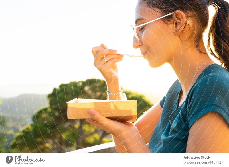 Crop woman enjoying delicious waffles against mountains in sunshine eat dessert treat cream whipped sweet takeaway box spoon eyeglasses belgian tasty smooth