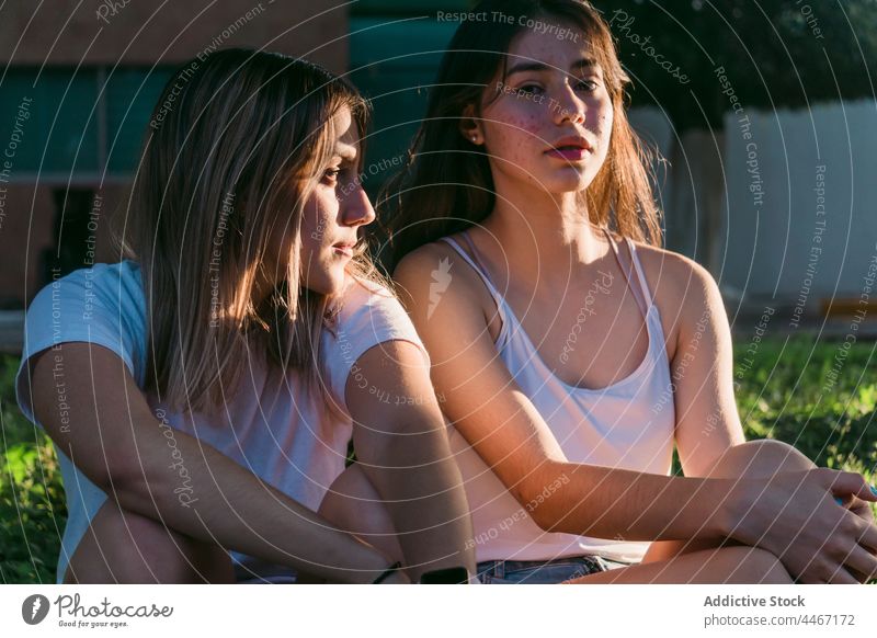 Girlfriends sitting in park girlfriend talk friendship spend time weekend cool pavement sun ray serious best friend rest trendy urban t shirt style enjoy